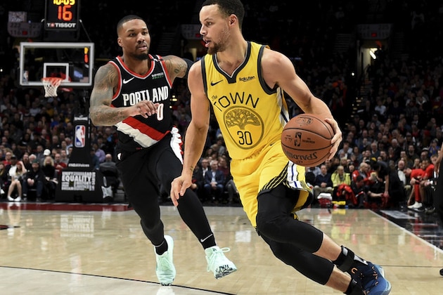 Golden State Warriors guard Stephen Curry, right, drives to the basket past Portland Trail Blazers guard Damian Lillard during the first half of an NBA basketball game in Portland, Ore., Wednesday, Feb. 13, 2019. (AP Photo/Steve Dykes)