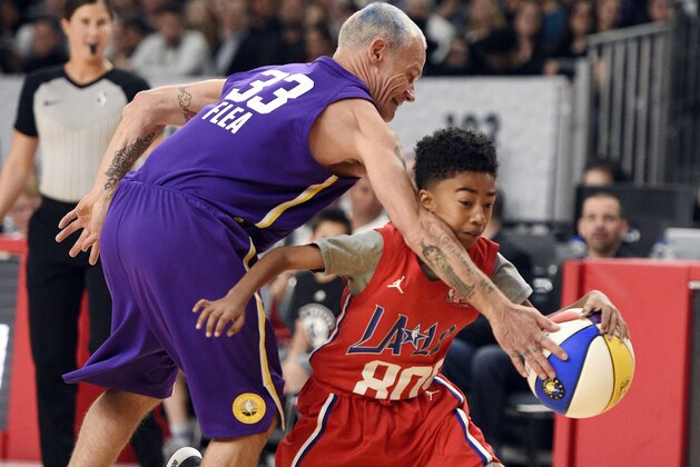 Actor Miles Brown, of Team Clippers, dribbles around musician Flea, of Team Lakers, during the NBA All-Star celebrity basketball game Friday, Feb. 16, 2018, in Los Angeles. (AP Photo/Chris Pizzello)