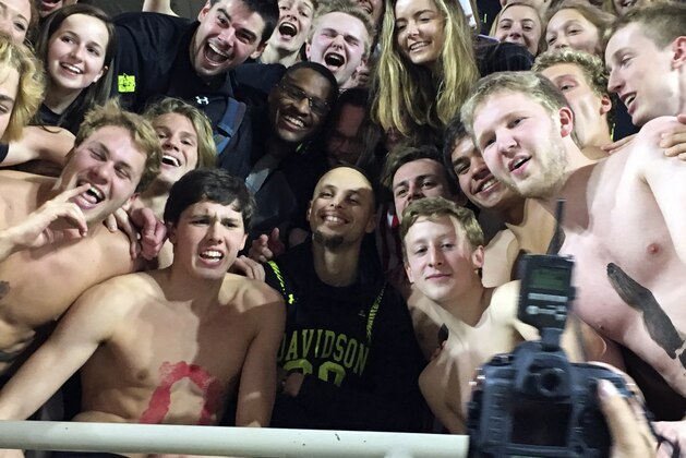 Golden State Warriors' Stephen Curry, center, poses with the Davidson College swim team as he takes in an NCAA college basketball game at his alma mater Friday, Feb. 15, 2019, while back in his hometown of Charlotte, N.C., for the NBA basketball All-Star game. (AP Photo/Steve Reed)