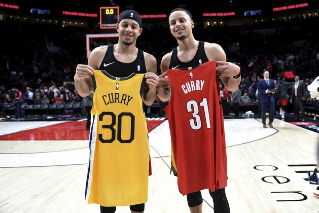 FILE - In this Dec. 29, 2018, file photo, Portland Trail Blazers guard Seth Curry, left, and his brother, Golden State Warriors guard Stephen Curry, exchange jerseys after an NBA basketball game in Portland, Ore. The Curry brothers are returning to their hometown of Charlotte, N.C, for the NBA All-Star weekend. Stephen, a two-time league MVP, will join younger brother Seth in the 3-point shootout on Saturday night at the Spectrum Center and then play in his sixth straight All-Star game on Sunday.  (AP Photo/Steve Dykes, File)