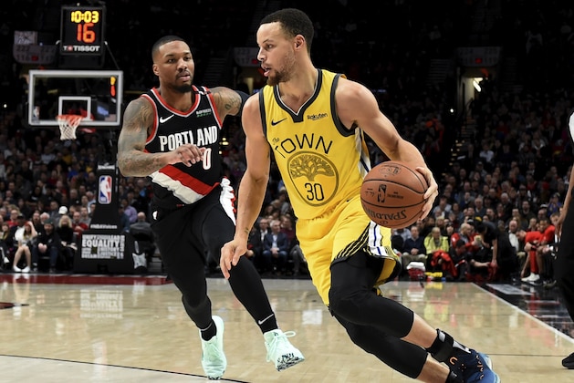Golden State Warriors guard Stephen Curry, right, drives to the basket past Portland Trail Blazers guard Damian Lillard during the first half of an NBA basketball game in Portland, Ore., Wednesday, Feb. 13, 2019. (AP Photo/Steve Dykes)