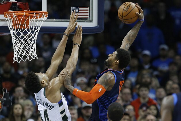 Oklahoma City Thunder forward Paul George, right, goes up for a dunk over Milwaukee Bucks forward Giannis Antetokounmpo (34) in the second half of an NBA basketball game in Oklahoma City, Sunday, Jan. 27, 2019. (AP Photo/Sue Ogrocki)