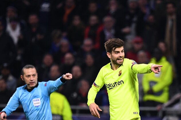 Turkish referee Cuneyt Cakir (L) and Barcelona's Spanish defender Gerard Pique (C) gesture  during the UEFA Champions League round of 16 first leg football match between Lyon (OL) and FC Barcelona on February 19, 2019, at the Groupama Stadium in Decines-Charpieu, central-eastern France. (Photo by FRANCK FIFE / AFP)        (Photo credit should read FRANCK FIFE/AFP/Getty Images)