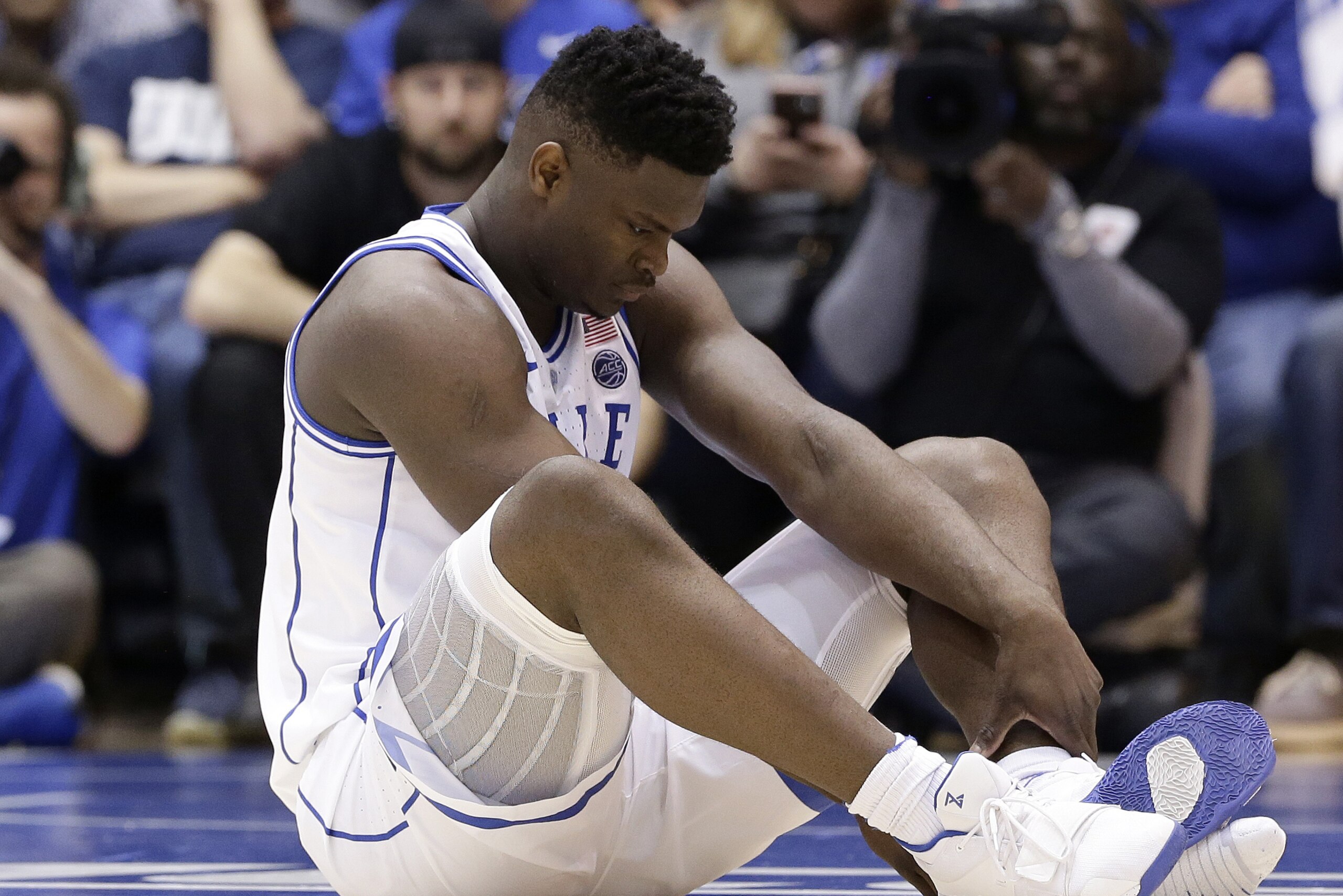 Duke's Zion Williamson sits on the floor following a injury during the first half of an NCAA college basketball game against North Carolina in Durham, N.C., Wednesday, Feb. 20, 2019. (AP Photo/Gerry Broome)