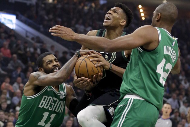 Boston Celtics' Kyrie Irving (11) forces a jump ball against Milwaukee Bucks' Giannis Antetokounmpo, center, during the first half of an NBA basketball game Thursday, Feb. 21, 2019, in Milwaukee. (AP Photo/Aaron Gash)