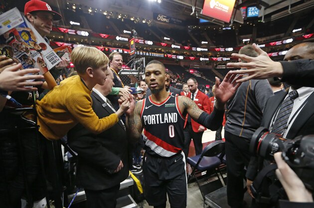 Fans reach for Portland Trail Blazers guard Damian Lillard (0) following the Blazers' 109-104 victory against the Utah Jazz in an NBA basketball game, Monday, Jan. 21, 2019, in Salt Lake City. (AP Photo/Rick Bowmer)