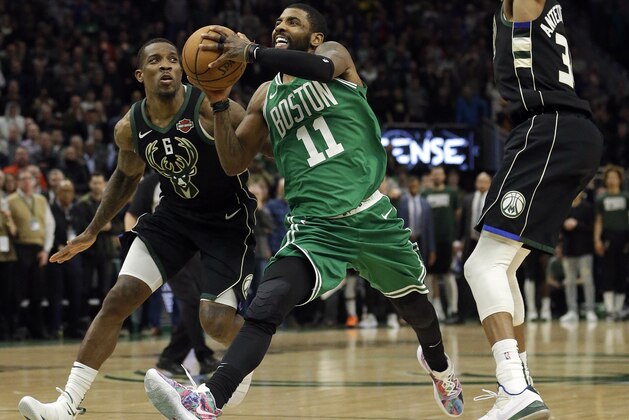 Boston Celtics' Kyrie Irving (11) drives between Milwaukee Bucks' Eric Bledsoe (6) and Giannis Antetokounmpo during the second half of an NBA basketball game Thursday, Feb. 21, 2019, in Milwaukee. (AP Photo/Aaron Gash)