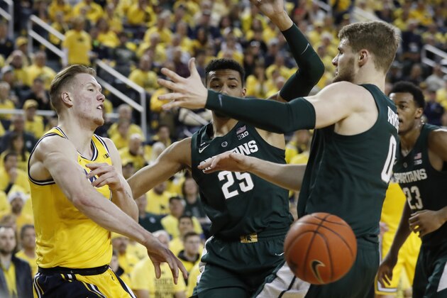 Michigan forward Ignas Brazdeikis, left, passes around Michigan State forward Kyle Ahrens (0) during the first half of an NCAA college basketball game, Sunday, Feb. 24, 2019, in Ann Arbor, Mich. (AP Photo/Carlos Osorio)