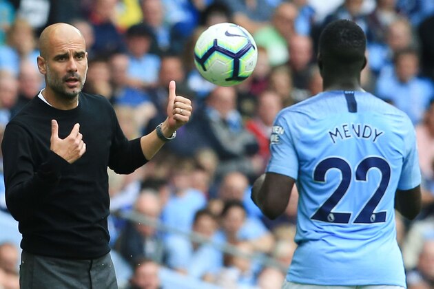 Manchester City's Spanish manager Pep Guardiola (L) throws the ball to Manchester City's French defender Benjamin Mendy (R) during the English Premier League football match between Manchester City and Huddersfield Town at the Etihad Stadium in Manchester, north west England, on August 19, 2018. (Photo by Lindsey PARNABY / AFP) / RESTRICTED TO EDITORIAL USE. No use with unauthorized audio, video, data, fixture lists, club/league logos or 'live' services. Online in-match use limited to 120 images. An additional 40 images may be used in extra time. No video emulation. Social media in-match use limited to 120 images. An additional 40 images may be used in extra time. No use in betting publications, games or single club/league/player publications. /         (Photo credit should read LINDSEY PARNABY/AFP/Getty Images)