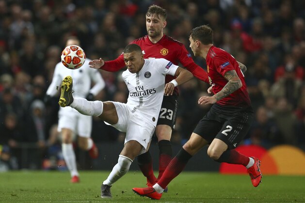 Paris Saint Germain's Kylian Mbappe, controls the ball under pressure from Manchester United's Luke Shaw, centre and Manchester United's Victor Linelof, right, during the Champions League round of 16 soccer match between Manchester United and Paris Saint Germain at Old Trafford stadium in Manchester, England, Tuesday, Feb. 12,2019.(AP Photo/Dave Thompson)