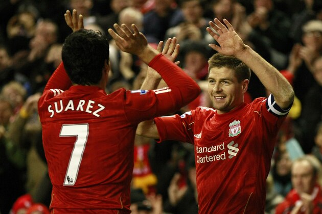 Liverpool's Steven Gerrard, right, celebrates with teammate Luis Suarez after Brighton and Hove Albion scored an own goal during their English FA Cup fifth round soccer match at Anfield, Liverpool, England, Sunday Feb. 19, 2012. (AP Photo/Tim Hales)