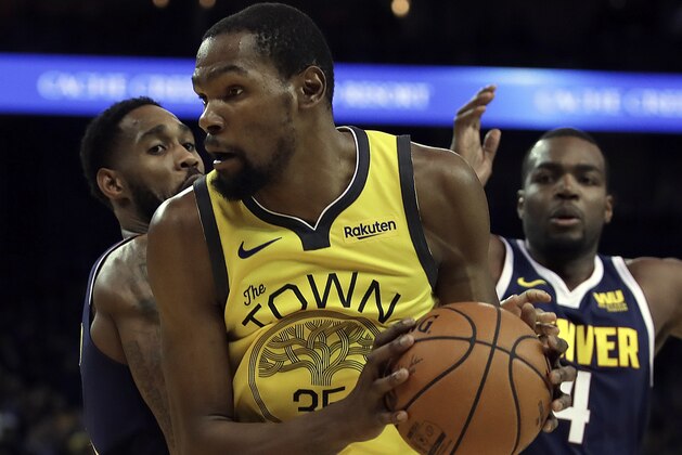 Golden State Warriors' Kevin Durant, center, looks to pass the ball away from Denver Nuggets' Will Barton, left, and Paul Millsap (4) during the second half of an NBA basketball game Friday, March 8, 2019, in Oakland, Calif. (AP Photo/Ben Margot)