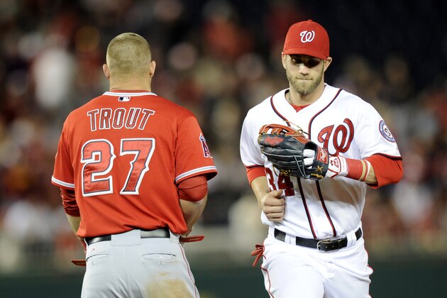 Washington Nationals left fielder Bryce Harper (34) runs from the field past Los Angeles Angels' Mike Trout (27) during the middle of the seventh inning of a baseball game, Monday, April 21, 2014, in Washington. The Angels won 4-2. (AP Photo/Nick Wass)