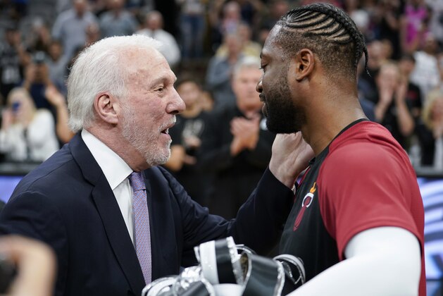 Miami Heat guard Dwyane Wade, right, accepts a gift from San Antonio Spurs coach Gregg Popovich before an NBA basketball game Wednesday, March 20, 2019, in San Antonio. (AP Photo/Darren Abate)