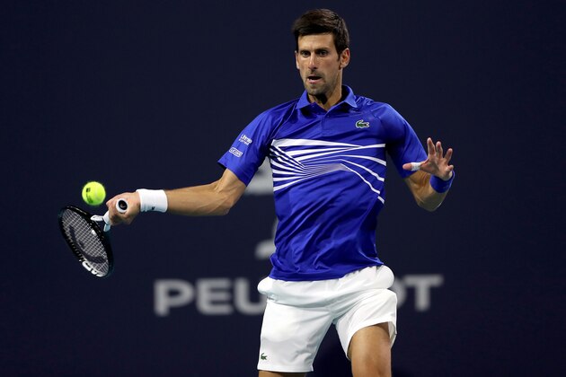 MIAMI GARDENS, FLORIDA - MARCH 22: Novak Djokovic of Serbia returns a shot to Bernard Tomic of Australia during the Miami Open Presented by Itau at Hard Rock Stadium March 22, 2019 in Miami Gardens, Florida. (Photo by Matthew Stockman/Getty Images)