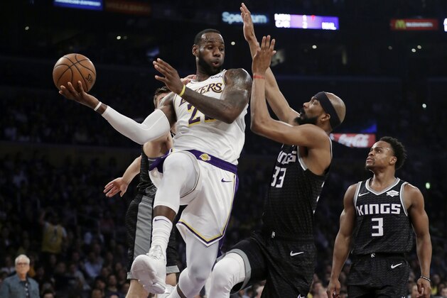 Los Angeles Lakers' LeBron James, left, makes a behind-the-back pass as Sacramento Kings' Corey Brewer (33) defends during the first half of an NBA basketball game Sunday, March 24, 2019, in Los Angeles. (AP Photo/Marcio Jose Sanchez)