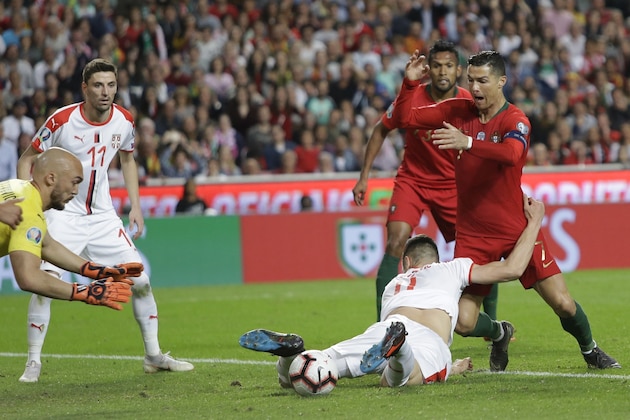 Serbia's Nikola Milenkovic, bottom, and Portugal's Cristiano Ronaldo challenge for the ball during the Euro 2020 group B qualifying soccer match between Portugal and Serbia at the Luz stadium in Lisbon, Portugal, Monday, March 25, 2019. (AP Photo/Armando Franca)
