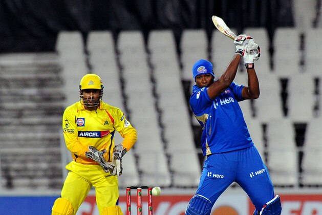 Mumbai Indians batsman/bowler Kieron Pollard (R) prepares to play a shot as Chennal Super Kings wicketkeeper Mahendra Singh Dhoni (L) watches on October 20, 2012 during a Group B  Champions League T20 (CLT20) match at Wanderers Stadium in Johannesburg.                 AFP PHOTO / ALEXANDER JOE        (Photo credit should read ALEXANDER JOE/AFP/Getty Images)