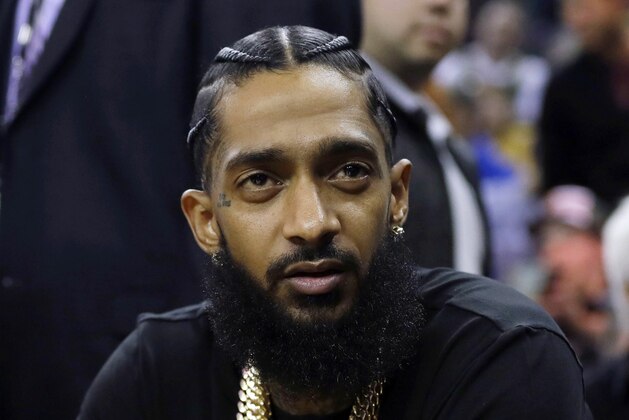 FILE - This March 29, 2018 file photo shows rapper Nipsey Hussle at an NBA basketball game between the Golden State Warriors and the Milwaukee Bucks in Oakland, Calif. Hussle was shot and killed Sunday, March 31, 2019 outside of his clothing store in Los Angeles. (AP Photo/Marcio Jose Sanchez, File)