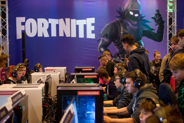 People play at computers with a Fortnite poster in the background during the Intel Extreme Masters Katowice 2019 event in Katowice on March 2, 2019. (Photo by BARTOSZ SIEDLIK / AFP)        (Photo credit should read BARTOSZ SIEDLIK/AFP/Getty Images)
