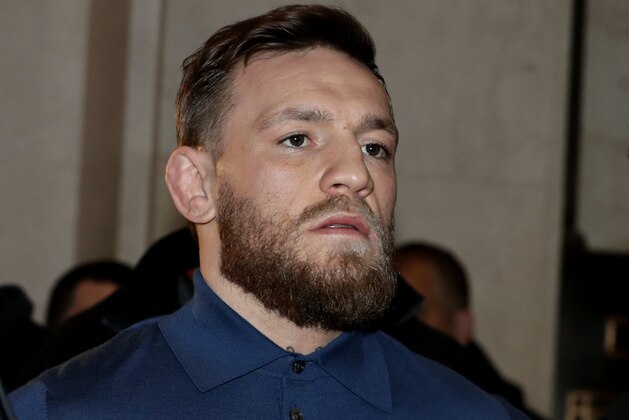 FILE - In this April 6, 2018 file photo, Ultimate fighting star Conor McGregor, center, is escorted by New York Court Police officers after a hearing at the Brooklyn Criminal Court, in New York. McGregor is due in court amid plea negotiations to resolve charges stemming from a backstage melee at a New York City arena. The 30-year-old Irish fighter is expected to be joined Thursday, July 26 in Brooklyn by his 25-year-old friend and co-defendant Cian Cowley.  (AP Photo/Julio Cortez, File)