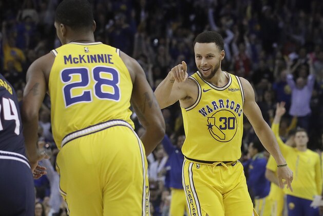 Golden State Warriors guard Stephen Curry (30) points toward teammate Alfonzo McKinnie after Curry scored against the Denver Nuggets during the second half of an NBA basketball game in Oakland, Calif., Tuesday, April 2, 2019. (AP Photo/Jeff Chiu)