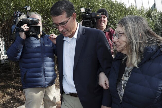 Michael Center, left, former Texas tennis coach, departs federal court in Boston with an unidentified woman on Thursday, March 28, 2019, after facing charges in a nationwide college admissions bribery scandal. (AP Photo/Charles Krupa)