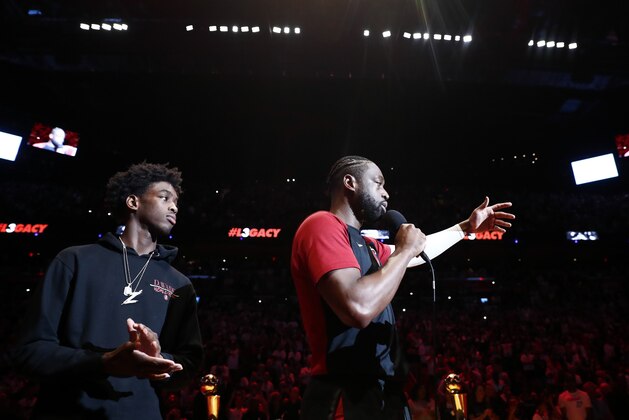 Miami Heat guard Dwyane Wade, right, speaks as his son Zaire looks on, during a ceremony to honor Wade who is playing his final home regular season game when the Heat host the Philadelphia 76ers, Tuesday, April 9, 2019, in Miami. Wade is retiring at the end of the season. (AP Photo/Brynn Anderson)