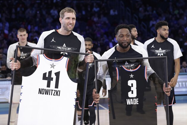 CORRECTS TO DWYANE, NOT SWAYNE - Team Giannis' Dirk Nowitzki, of the Dallas Mavericks, and Team LeBron's Dwyane Wade, of the Miami Heat, are given jerseys during the second half of an NBA All-Star basketball game, Sunday, Feb. 17, 2019, in Charlotte, N.C. The Team LeBron won 178-164. (AP Photo/Chuck Burton)
