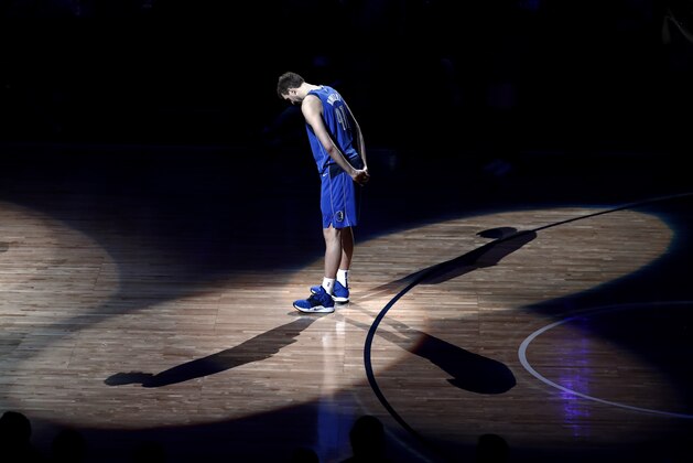 Dallas Mavericks forward Dirk Nowitzki stands on the court listening as former players pay tribute to him after the team's NBA basketball game against the Phoenix Suns in Dallas, Tuesday, April 9, 2019. (AP Photo/Tony Gutierrez)