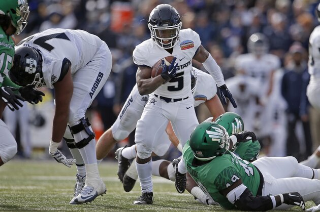 Utah State running back Darwin Thompson (5) tries to avoid the North Texas defense during the first half of the New Mexico Bowl NCAA college football game in Albuquerque, N.M., Saturday, Dec. 15, 2018. (AP Photo/Andres Leighton)