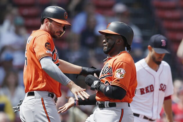 Baltimore Orioles' Dwight Smith Jr., left, and Trey Mancini, center, celebrate after scoring on single by Chris Davis off Boston Red Sox's Rick Porcello, right, during the first inning of a baseball game in Boston, Saturday, April 13, 2019. (AP Photo/Michael Dwyer)