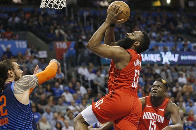 Houston Rockets guard James Harden (13) goes up for a shot between Oklahoma City Thunder center Steven Adams, left, and Rockets' Clint Capela (15) during the first half of an NBA basketball game Tuesday, April 9, 2019, in Oklahoma City. (AP Photo/Sue Ogrocki)