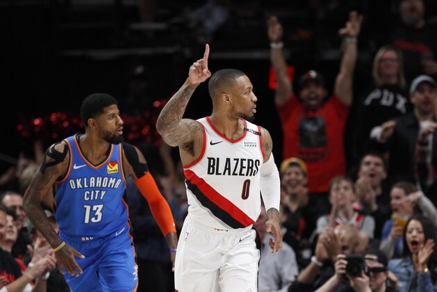 Portland Trail Blazers guard Damian Lillard, right, reacts after making a basket as Oklahoma City Thunder forward Paul George, left, trails the play during the first half of Game 1 of a first-round NBA basketball playoff series in Portland, Ore., Sunday, April 14, 2019. (AP Photo/Steve Dipaola)
