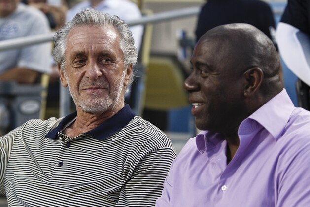 Los Angeles Dodgers part owner and former Los Angeles Lakers player Magic Johnson, right, and former Lakers coach Pat Riley watch the Dodgers in the first inning of a baseball game against the San Francisco Giants in Los Angeles, Wednesday, Aug. 22, 2012. (AP Photo/Jason Redmond)