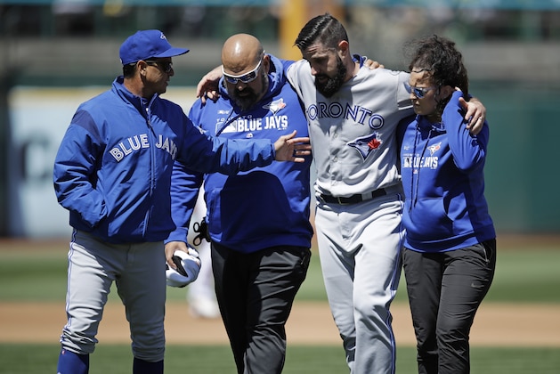 Toronto Blue Jays manager Charlie Montoyo, left, speaks with pitcher Matt Shoemaker, second from right, as Shoemaker is helped off the field after sustaining an injury during a rundown play against the Oakland Athletics in the third inning of a baseball game Saturday, April 20, 2019, in Oakland, Calif. (AP Photo/Ben Margot)
