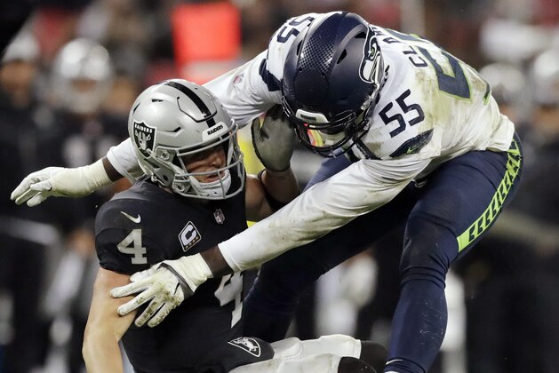 ARCHIVO- En imagen de archivo del 14 de octubre de 2018, el quarterback Derek Carr (4), de los Raiders de Oakland, es capturado por el defensive end Frank Clark (55), de los Seahawks de Seattle, en partido de la NFL en el estadio Wembley de Londres. (AP Foto/Matt Dunham, archivo)