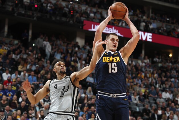 Denver Nuggets center Nikola Jokic, right, pulls in a rebound as San Antonio Spurs guard Derrick White defends in the first half of Game 7 of an NBA basketball first-round playoff series Saturday, April 27, 2019, in Denver. (AP Photo/David Zalubowski)