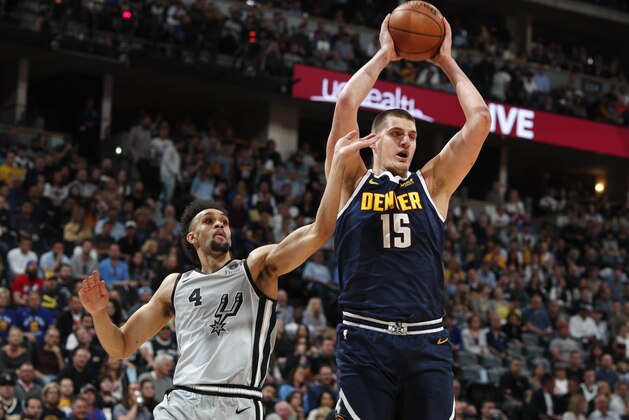 Denver Nuggets center Nikola Jokic, right, pulls in a rebound as San Antonio Spurs guard Derrick White defends in the first half of Game 7 of an NBA basketball first-round playoff series Saturday, April 27, 2019, in Denver. (AP Photo/David Zalubowski)