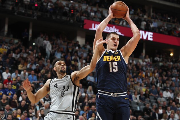Denver Nuggets center Nikola Jokic, right, pulls in a rebound as San Antonio Spurs guard Derrick White defends in the first half of Game 7 of an NBA basketball first-round playoff series Saturday, April 27, 2019, in Denver. (AP Photo/David Zalubowski)
