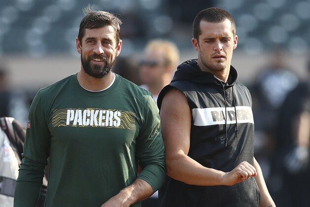 Green Bay Packers quarterback Aaron Rodgers, left, talks with Oakland Raiders quarterback Derek Carr before an NFL preseason football game in Oakland, Calif., Friday, Aug. 24, 2018. (AP Photo/Ben Margot)