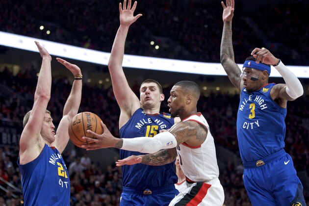 Portland Trail Blazers guard Damian Lillard, center, passes the ball away from Denver Nuggets forward Mason Plumlee, left, center Nikola Jokic, second from left, and forward Torrey Craig, right, during overtime of Game 3 of an NBA basketball second-round playoff series Friday, May 3, 2019, in Portland, Ore. (AP Photo/Craig Mitchelldyer)