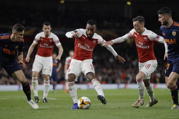 Arsenal's Alexandre Lacazette, center, controls the ball between Valencia's Gabriel, left, his teammate Mesut Ozil and Valencia's Cristiano Piccini, right, during the Europa League semifinal first leg soccer match between Arsenal and Valencia at the Emirates stadium in London, Thursday, May 2, 2019. (AP Photo/Kirsty Wigglesworth)