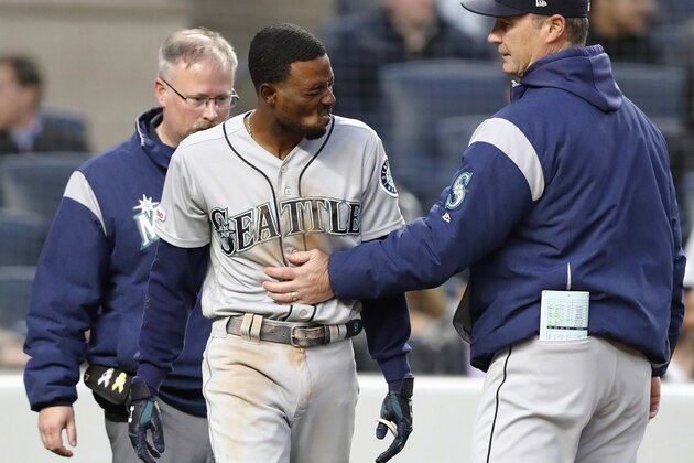 Seattle Mariners manager Scott Servais, right, and a Mariners trainer check on Dee Gordon, center, who was hit by a pitch during the third inning of the team's baseball game against the New York Yankees, Thursday, May 9, 2019, in New York. Gordon was removed from the game. (AP Photo/Kathy Willens)