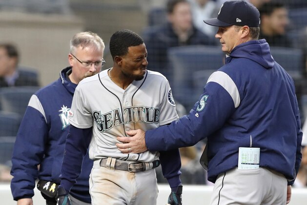 Seattle Mariners manager Scott Servais, right, and a Mariners trainer check on Dee Gordon, center, who was hit by a pitch during the third inning of the team's baseball game against the New York Yankees, Thursday, May 9, 2019, in New York. Gordon was removed from the game. (AP Photo/Kathy Willens)