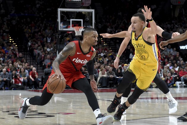 Portland Trail Blazers guard Damian Lillard, left, drives as Golden State Warriors guard Stephen Curry defends during the second half of an NBA basketball game in Portland, Ore., Saturday, Dec. 29, 2018. The Warriors won 115-105. (AP Photo/Steve Dykes)