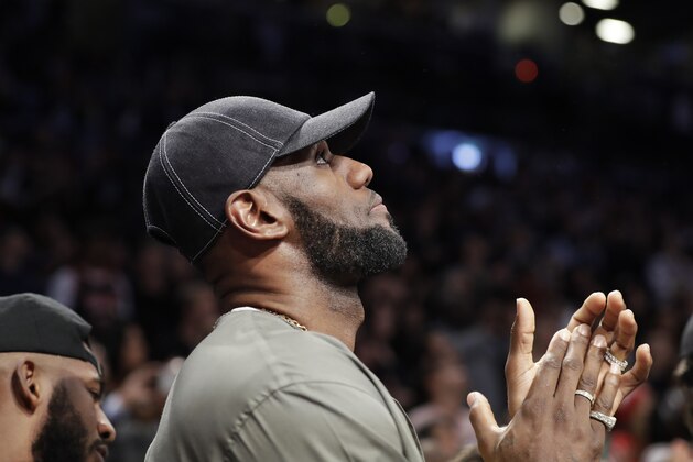 LeBron James applauds as he watches on a giant overhead video screen as a member of the military is honored during a timeout in the first half of an NBA basketball game between the Brooklyn Nets and the Miami Heat, Wednesday, April 10, 2019, in New York. James and other NBA stars, including Houston Rockets Chris Paul, left, turned out to watch final game of Miami Heat guard Dwyane Wade's NBA career. (AP Photo/Kathy Willens)