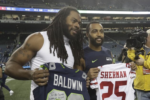 Seattle Seahawks wide receiver Doug Baldwin, right, and San Francisco 49ers cornerback Richard Sherman, left, pose for a photo after they traded jerseys following an NFL football game, Sunday, Dec. 2, 2018, in Seattle. The Seahawks won 43-16. (AP Photo/Elaine Thompson)