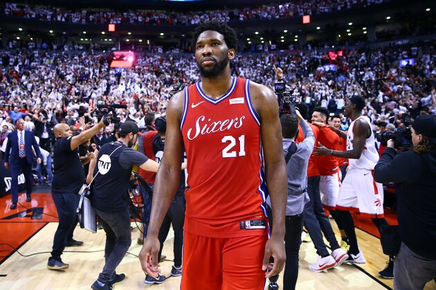 TORONTO, ON - MAY 12:  Joel Embiid #21 of the Philadelphia 76ers looks on as Kawhi Leonard #2 of the Toronto Raptors celebrates with teammates after sinking a buzzer beater to win Game Seven of the second round of the 2019 NBA Playoffs at Scotiabank Arena on May 12, 2019 in Toronto, Canada.  NOTE TO USER: User expressly acknowledges and agrees that, by downloading and or using this photograph, User is consenting to the terms and conditions of the Getty Images License Agreement.  (Photo by Vaughn Ridley/Getty Images)