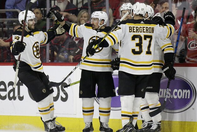 Boston Bruins' Jake DeBrusk, left, celebrates with Brad Marchand, Patrice Bergeron (37) and teammates following Marchand's goal against the Carolina Hurricanes during the second period in Game 3 of the NHL hockey Stanley Cup Eastern Conference final series in Raleigh, N.C., Tuesday, May 14, 2019. (AP Photo/Gerry Broome)